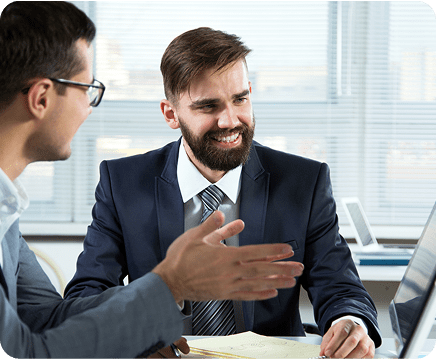 T4T Academy - 2 homens em mesa de trabalho, discutindo soluções na frente do computador, vestindo terno.